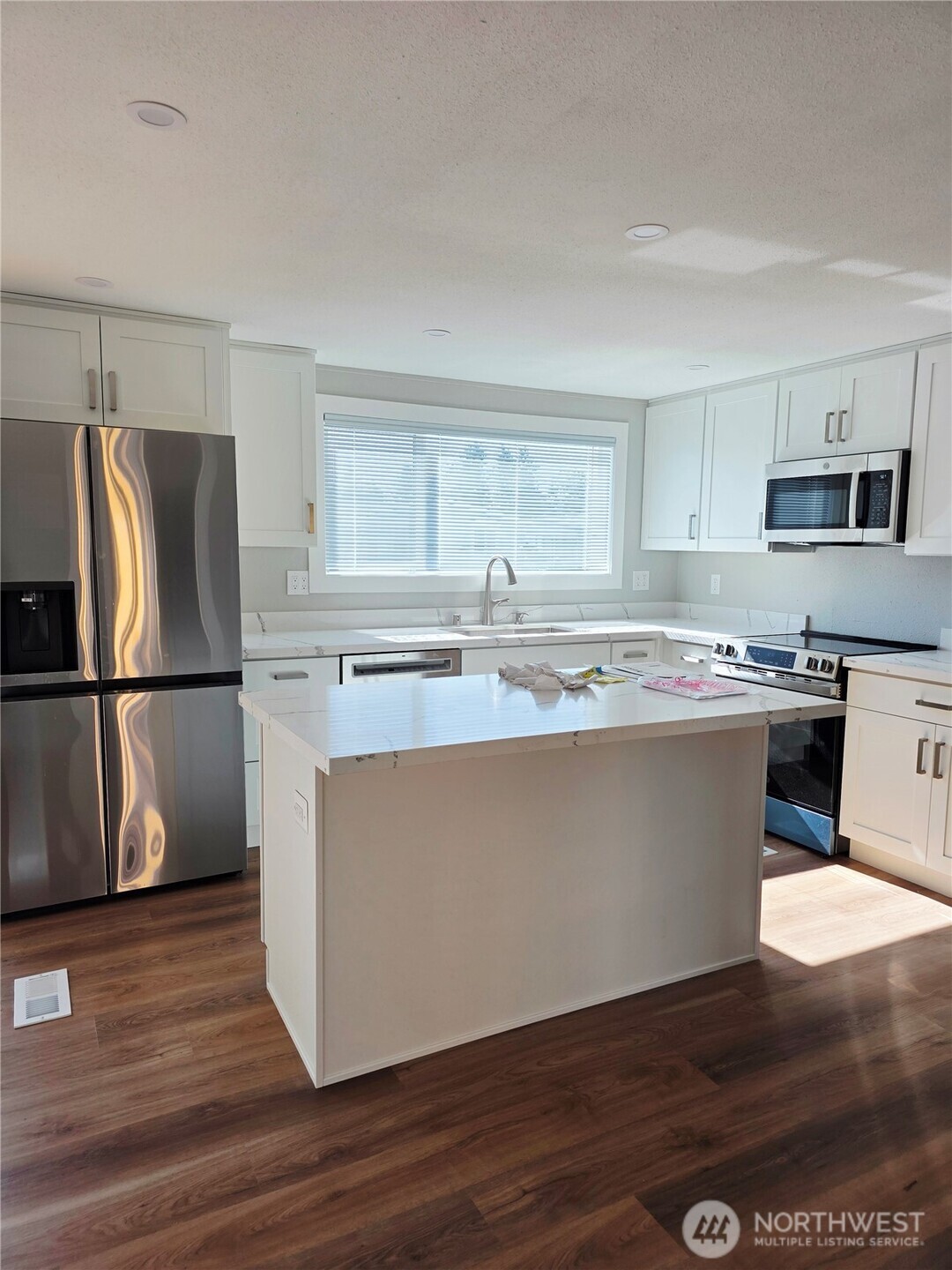 836 South Harmon Way, Unit 73 Orting, WA 98360 - Photo 12 of 30 a kitchen with wooden floors white cabinets and stainless steel appliances