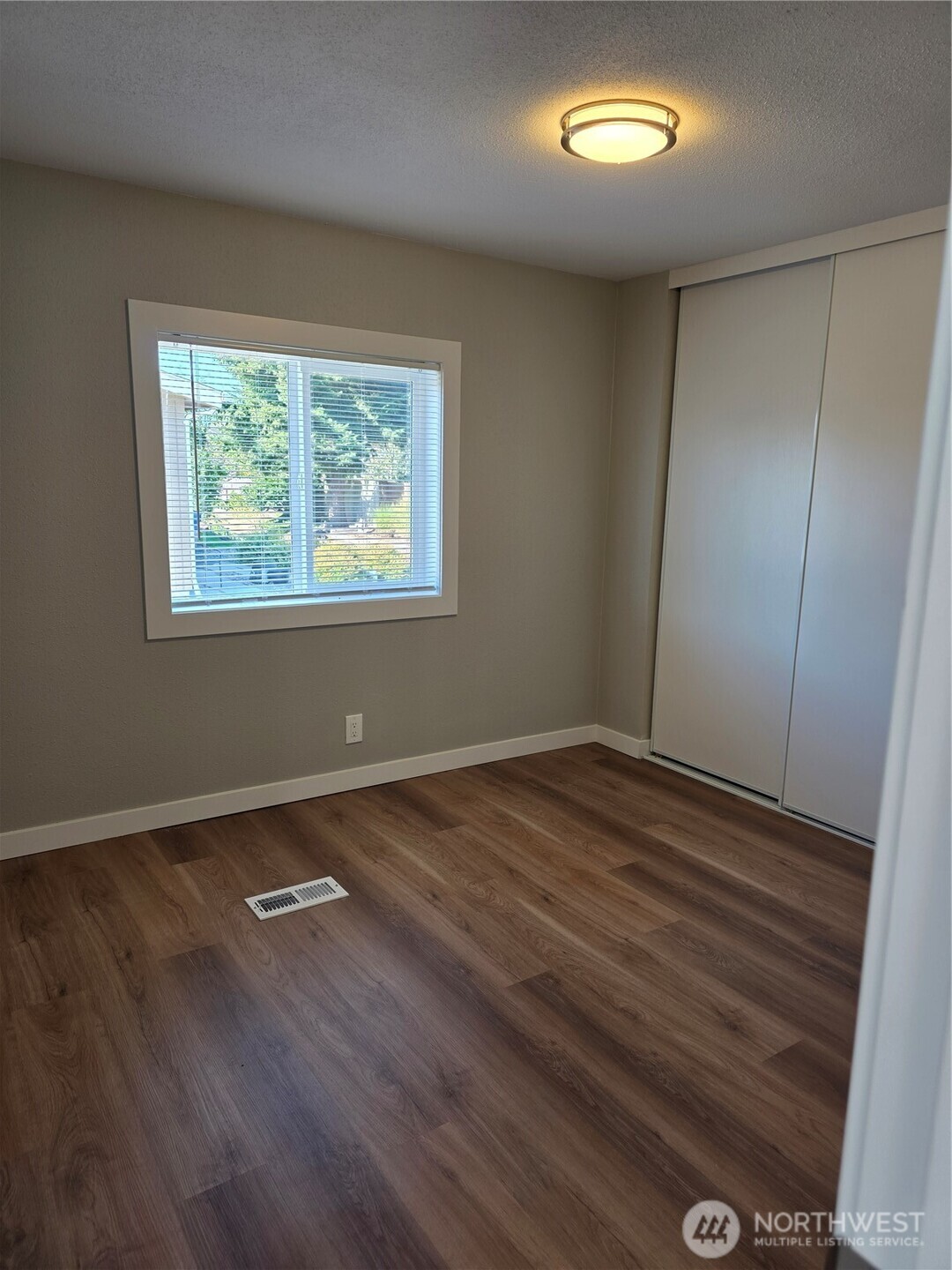 836 South Harmon Way, Unit 73 Orting, WA 98360 - Photo 20 of 30 an empty room with wooden floor and windows