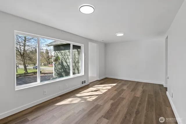 a view of an empty room with wooden floor and a window