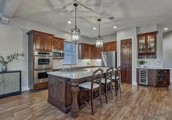 a kitchen with stainless steel appliances a dining table chairs stove and refrigerator