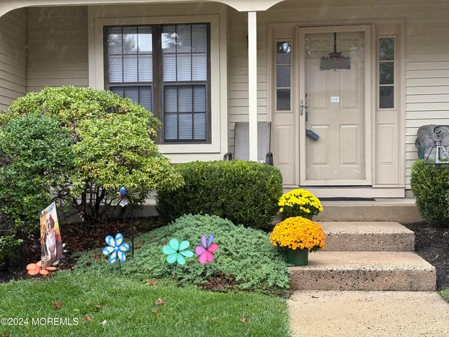 a front view of a house with lots of flower and a garden