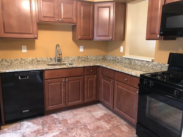 a kitchen with granite countertop a sink stainless steel appliances and cabinets