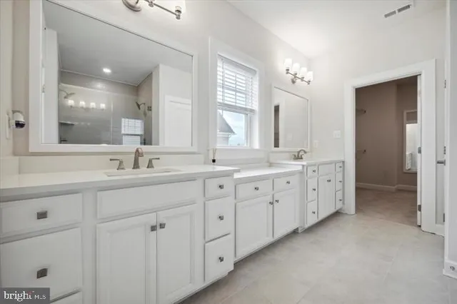 a spacious bathroom with double sink and a mirror
