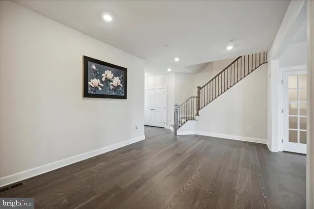 a view of an empty room with wooden floor and stairs