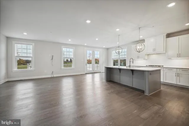 a large kitchen with stainless steel appliances granite countertop a large counter top a wooden floors and a large window