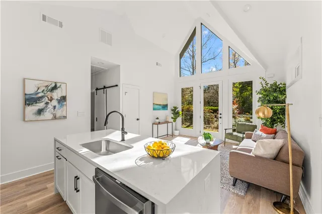 a kitchen with stainless steel appliances granite countertop a stove a sink and white cabinets with wooden floors