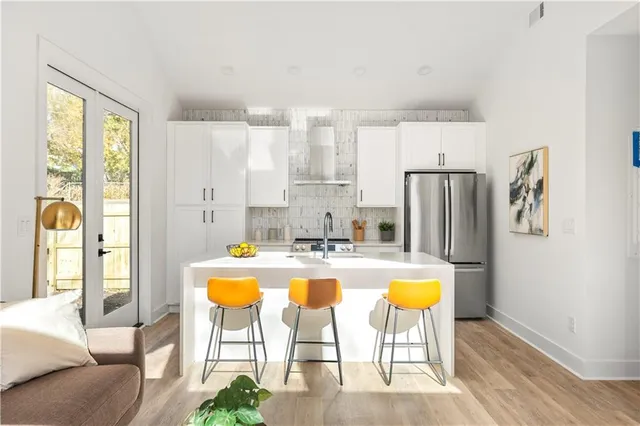 a kitchen with stainless steel appliances granite countertop a refrigerator a stove a sink dishwasher and white cabinets with wooden floor