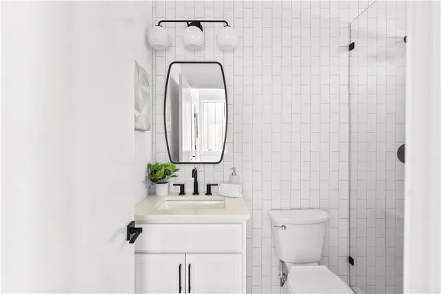 a bathroom with a toilet sink vanity granite and shower