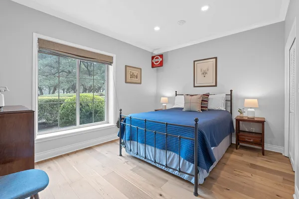 a bedroom with a bed a window and wooden floor