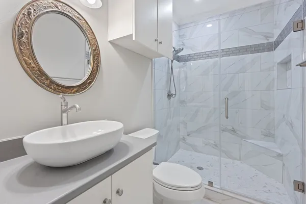 a bathroom with a sink a mirror a toilet and a shower