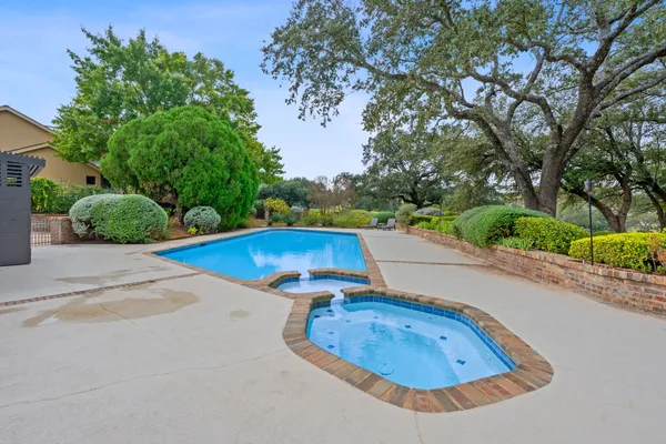an aerial view of a swimming pool with an outdoor space and seating area