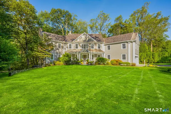 a view of a white house with a big yard and large trees