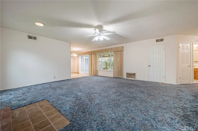 an empty room with windows and ceiling fan