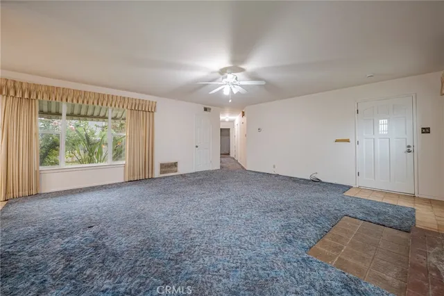 a view of a big room with windows and chandelier fan