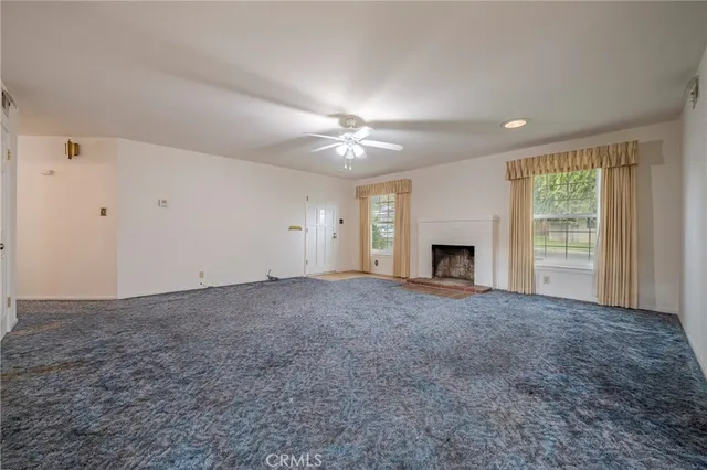 a view of a room with a ceiling fan and a fireplace