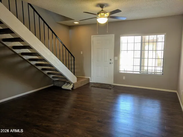 a view of an empty room with wooden floor stairs and a window