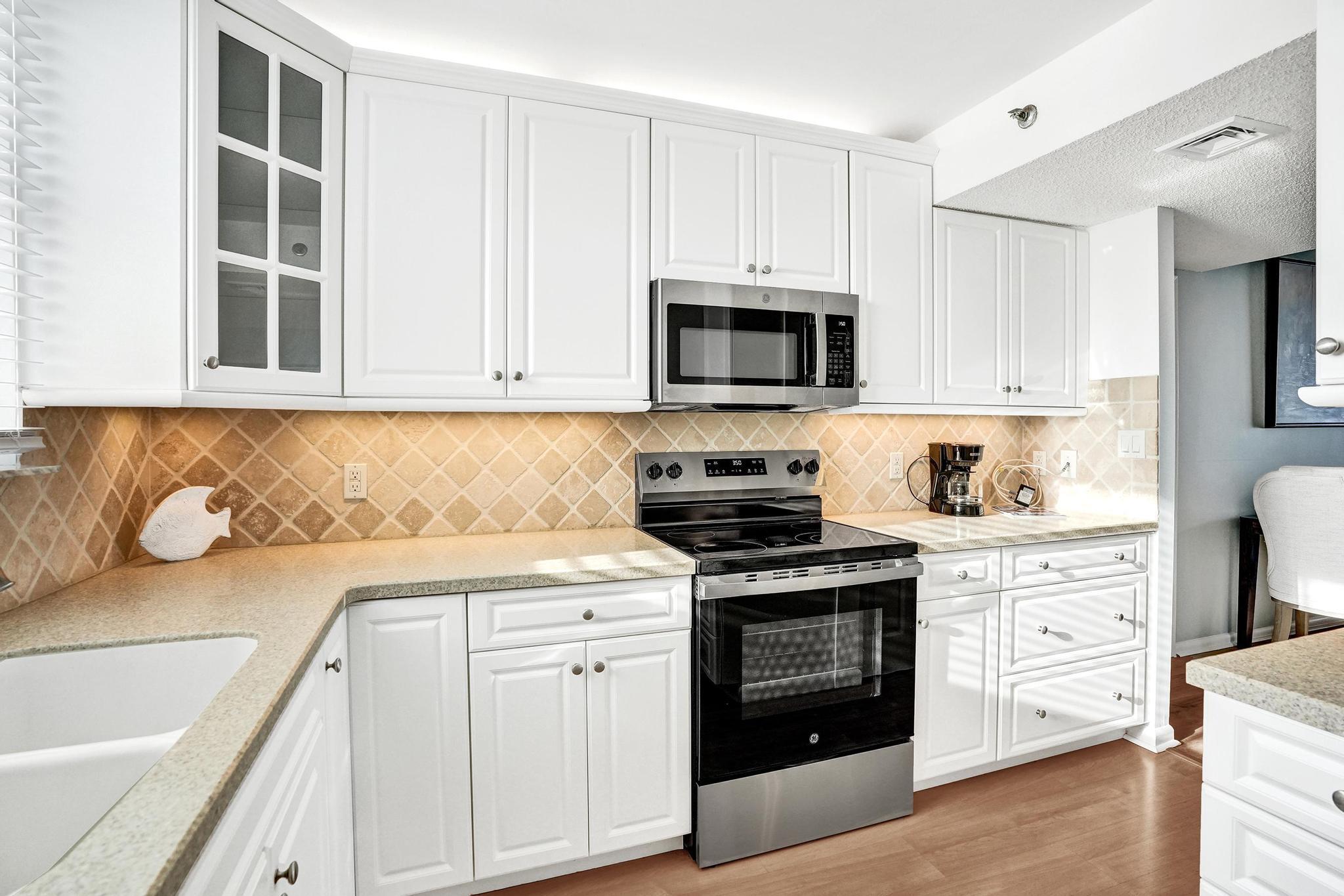 300 Ocean Trail Way, Unit 410 Jupiter, FL 33477 - Photo 19 of 58 a kitchen with stainless steel appliances granite countertop a stove a sink and a microwave