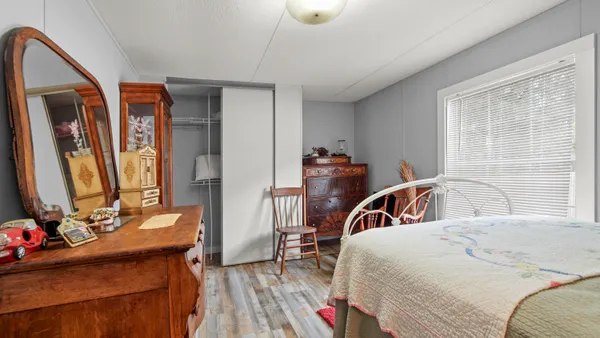 a bedroom with a bed and a large mirror on the dresser