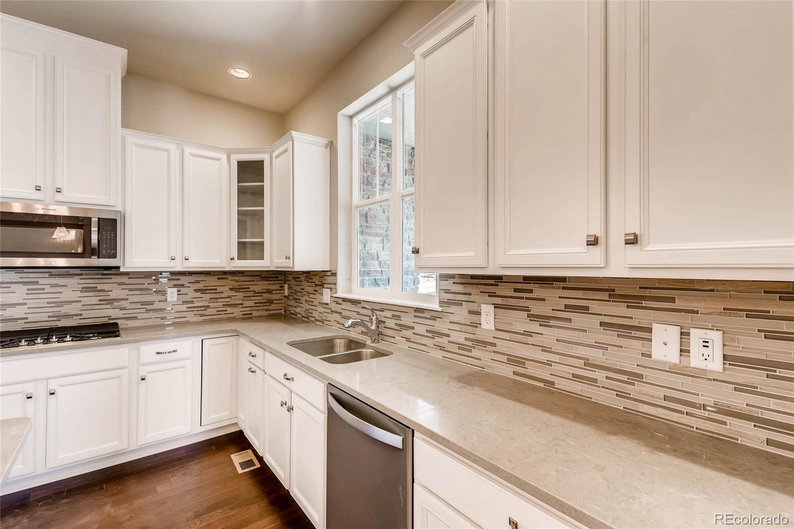 5052 West 109th Circle Westminster, CO 80031 - Photo 11 of 30 a kitchen with stainless steel appliances granite countertop a stove a sink and white cabinets