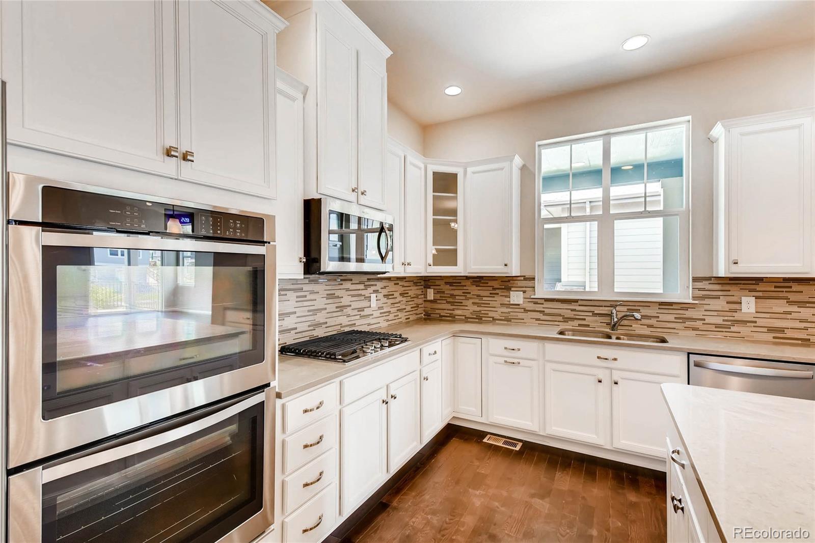5052 West 109th Circle Westminster, CO 80031 - Photo 12 of 30 a kitchen with granite countertop white cabinets and white appliances