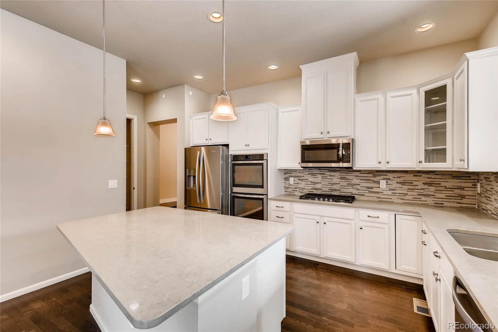 5052 West 109th Circle Westminster, CO 80031 - Photo 10 of 30 a kitchen with stainless steel appliances a stove sink microwave and cabinets