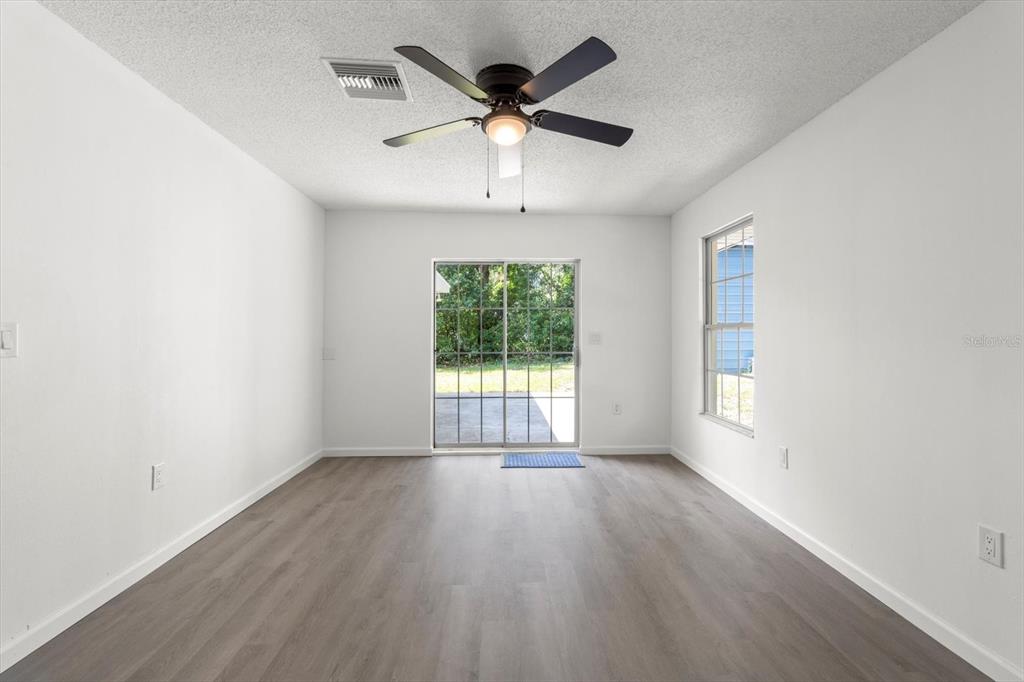 5700 South Calgary Terrace Inverness, FL 34452 - Photo 8 of 39 an empty room with wooden floor chandelier fan and windows