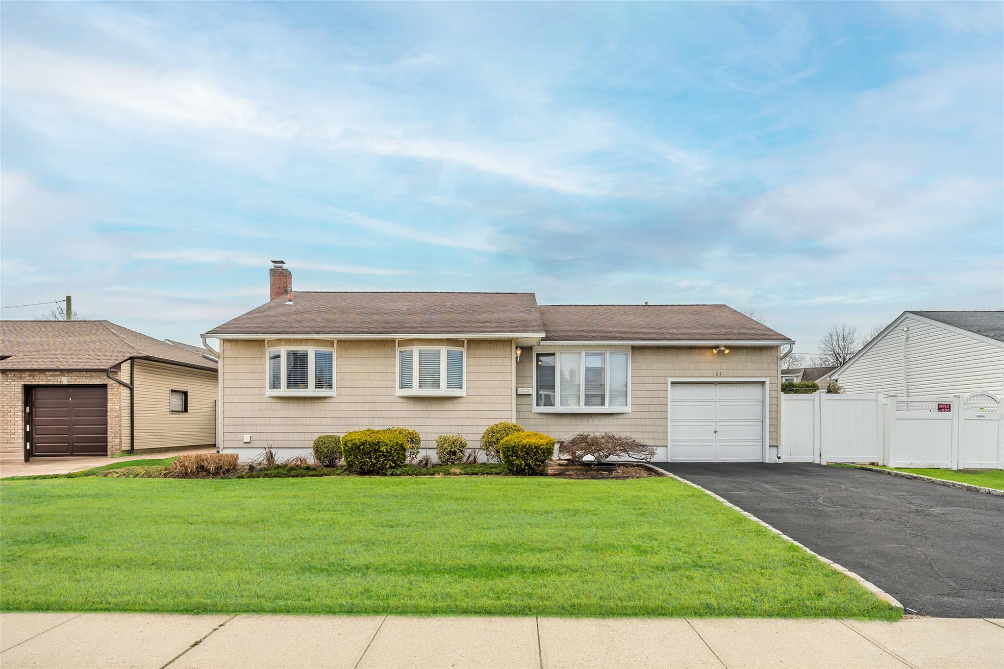 Ranch-style house featuring fence, driveway, a front yard, a garage, and a chimney
