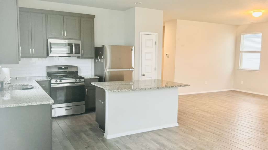 1305 Goforth Road Kyle, TX 78640 - Photo 9 of 23 Kitchen featuring stainless steel appliances, light stone counters, dark wood-type flooring, a kitchen island, and tasteful backsplash