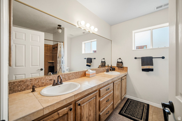 1985 West Rivers Edge Lane St. George, UT 84770 - Photo 28 of 42 Full bathroom with double vanity, a shower with curtain, and light tile patterned floors