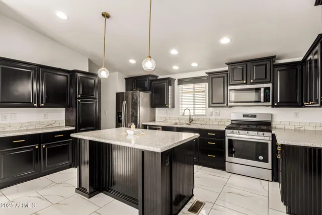 a kitchen with stainless steel appliances kitchen island granite countertop a sink stove and refrigerator