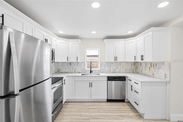 a kitchen with white cabinets and stainless steel appliances