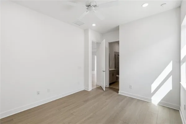 an empty room with wooden floor and a ceiling fan