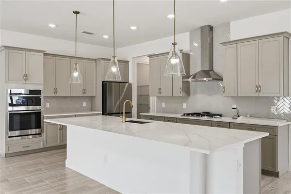 a kitchen with stainless steel appliances granite countertop a sink a stove a refrigerator and white cabinets