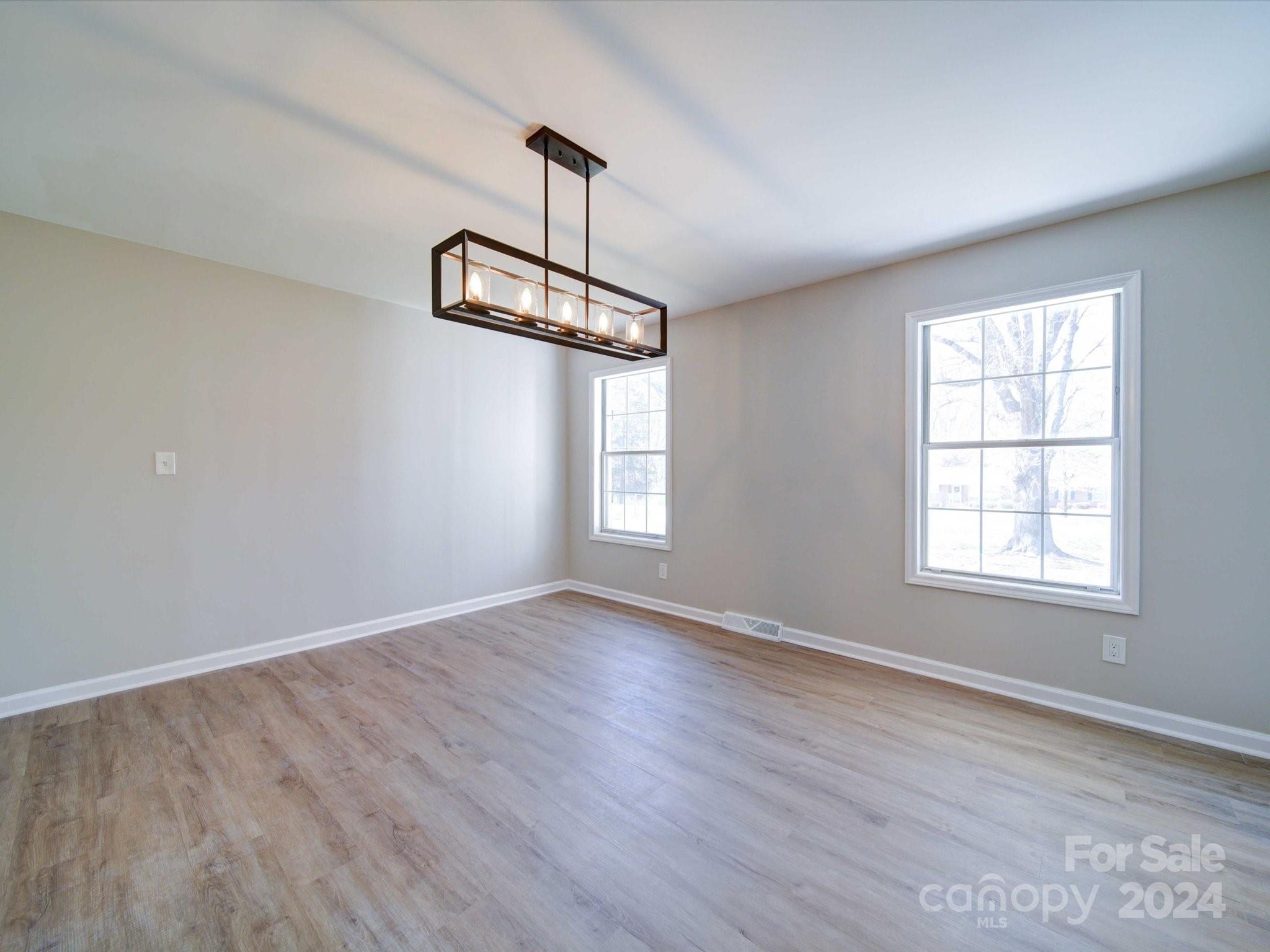 101 Hedgestone Drive Gastonia, NC 28056 - Photo 13 of 39 an empty room with wooden floor chandelier and windows
