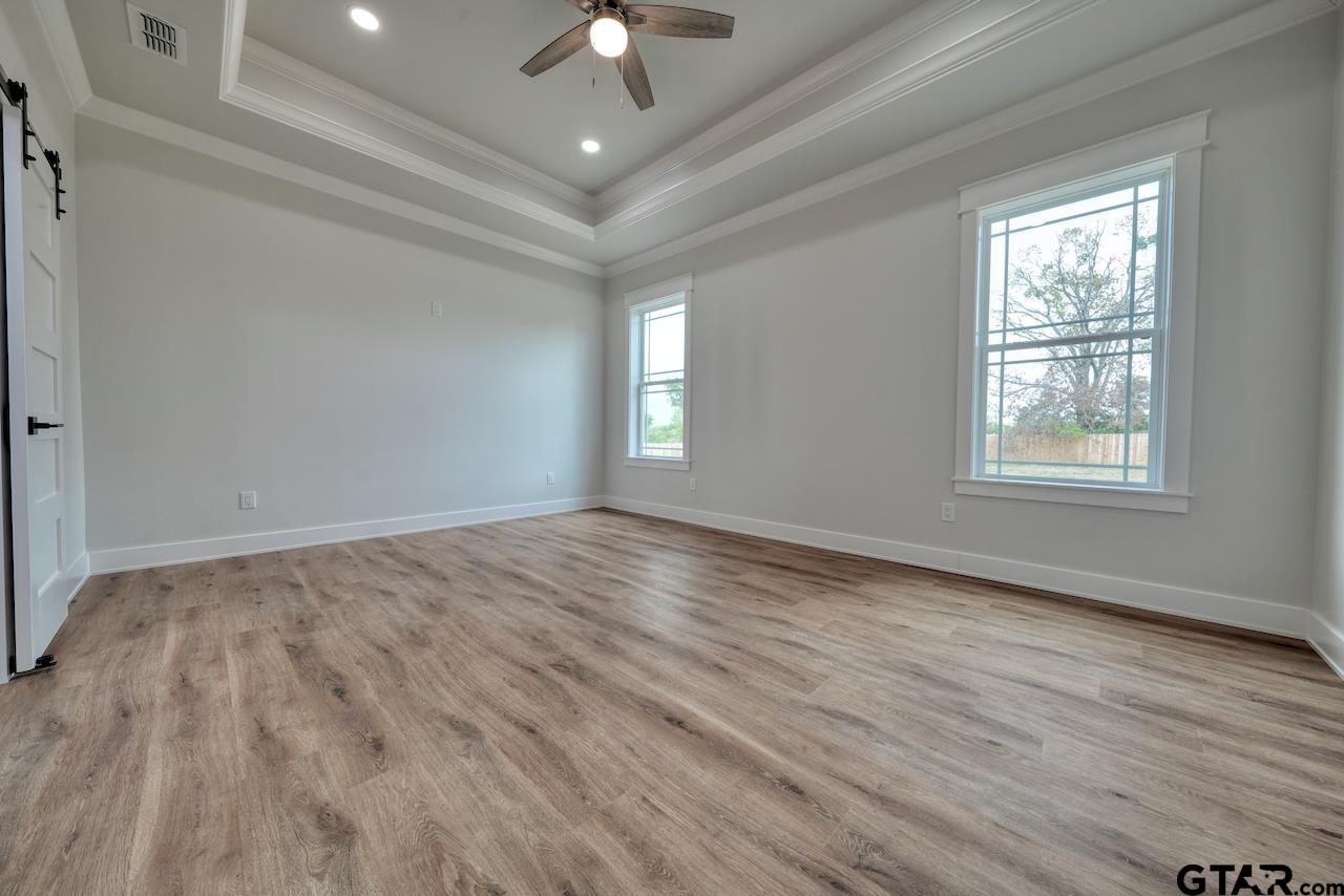 19383 Ridge Point Circle Lindale, TX 75771 - Photo 22 of 48 an empty room with wooden floor chandelier fan and windows