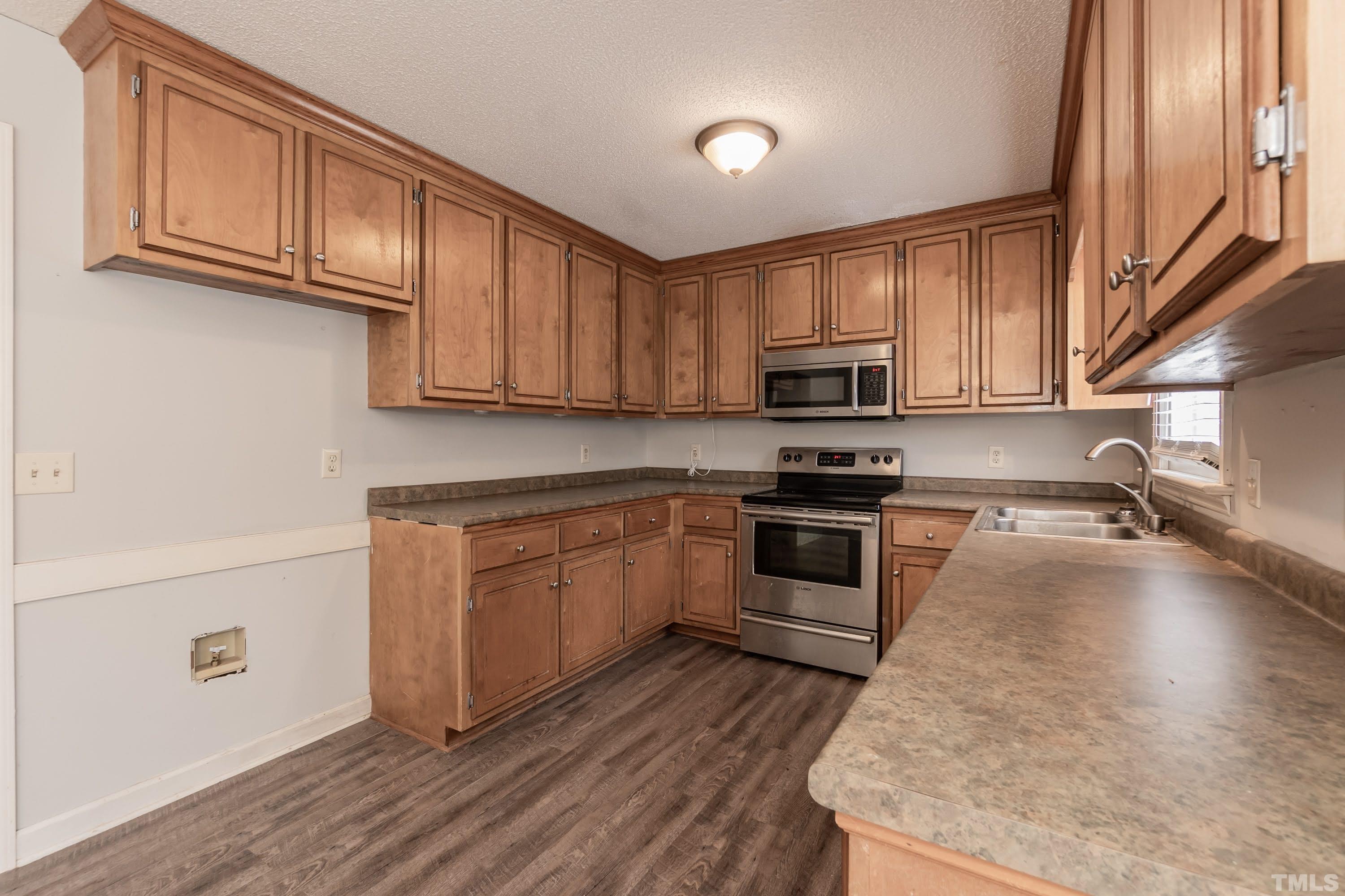 9117 Ferrell Road Zebulon, NC 27597 - Photo 8 of 26 a kitchen with granite countertop a sink a stove top oven and cabinetry