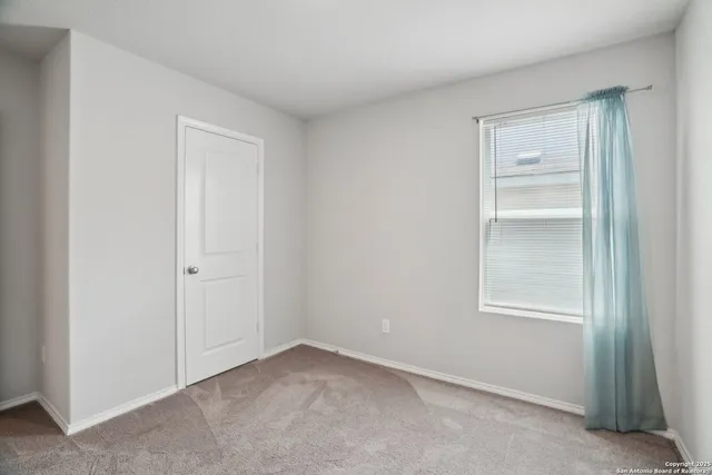 a view of an empty room with closet and a window