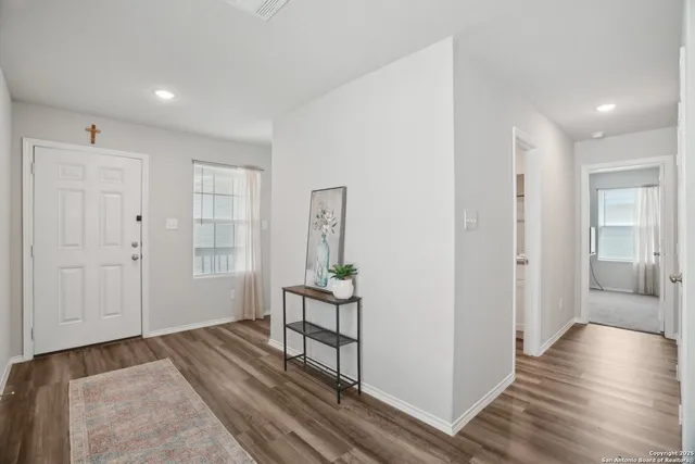 a view of a hallway with wooden floor and cabinet