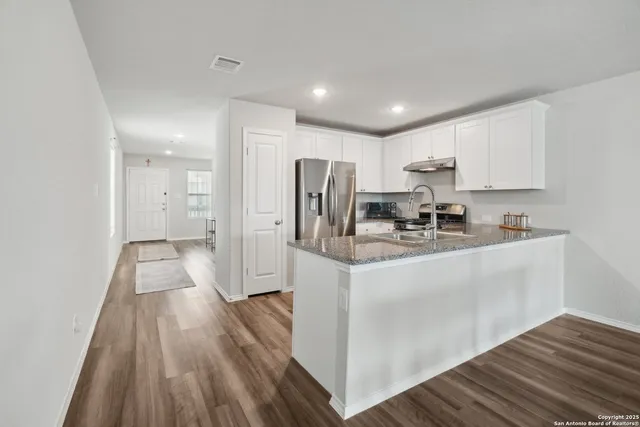 a kitchen with kitchen island wooden floors appliances and cabinets