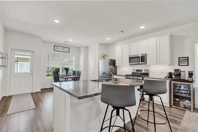 a kitchen with sink refrigerator dining table and chairs