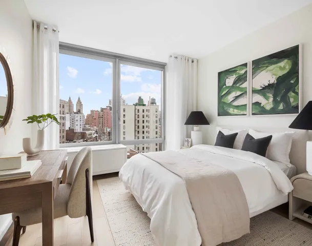 a large white bed sitting in a bedroom next to a window