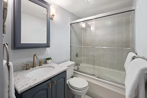 a bathroom with a granite countertop sink a toilet and shower