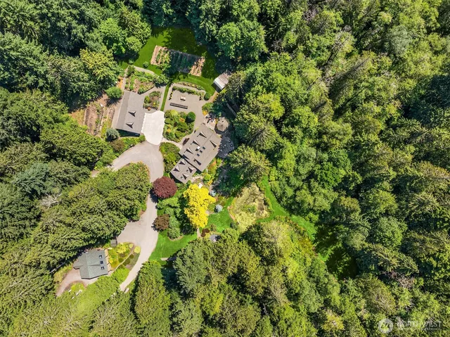 an aerial view of residential house with outdoor space and trees all around