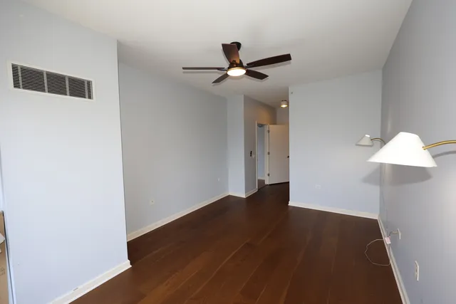 an empty room with wooden floor fan and windows
