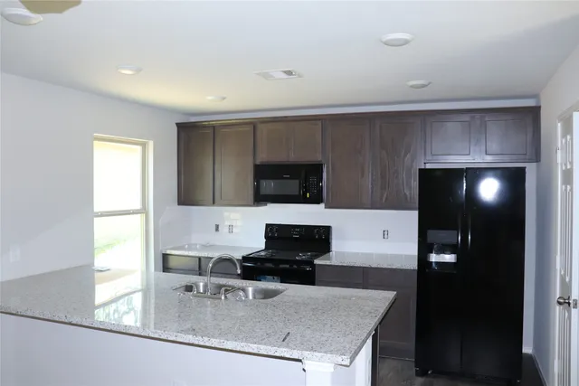 a kitchen with a sink a microwave a refrigerator and cabinets