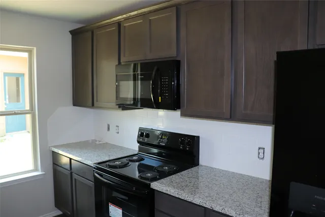 a kitchen with granite countertop cabinets and stove top oven