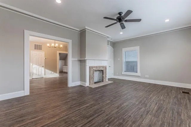 a view of a livingroom with wooden floor a ceiling fan and windows