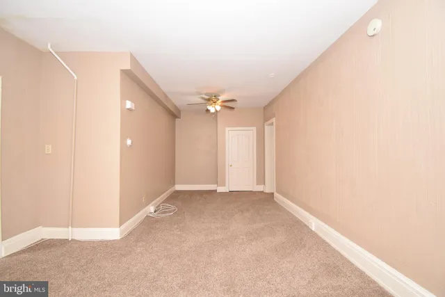 an empty room with an entryway and chandelier fan