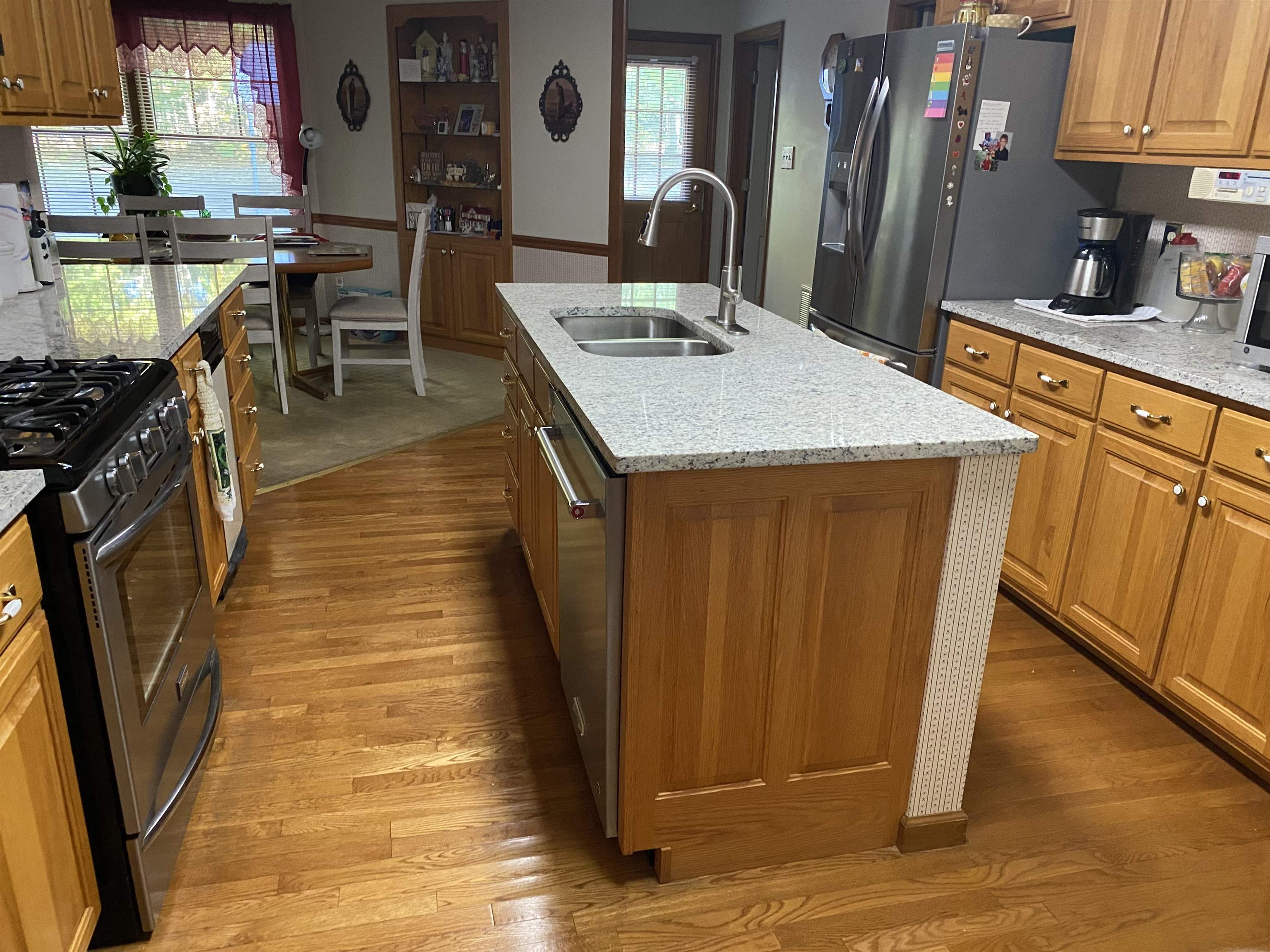 883 Crucifer Road Huron, TN 38345 - Photo 9 of 22 Kitchen featuring brown cabinetry, light granite countertops, appliances with stainless steel finishes, an island with sink, and healthy amount of natural light