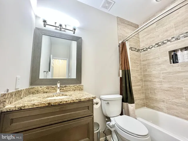 a bathroom with a granite countertop toilet a sink and a mirror